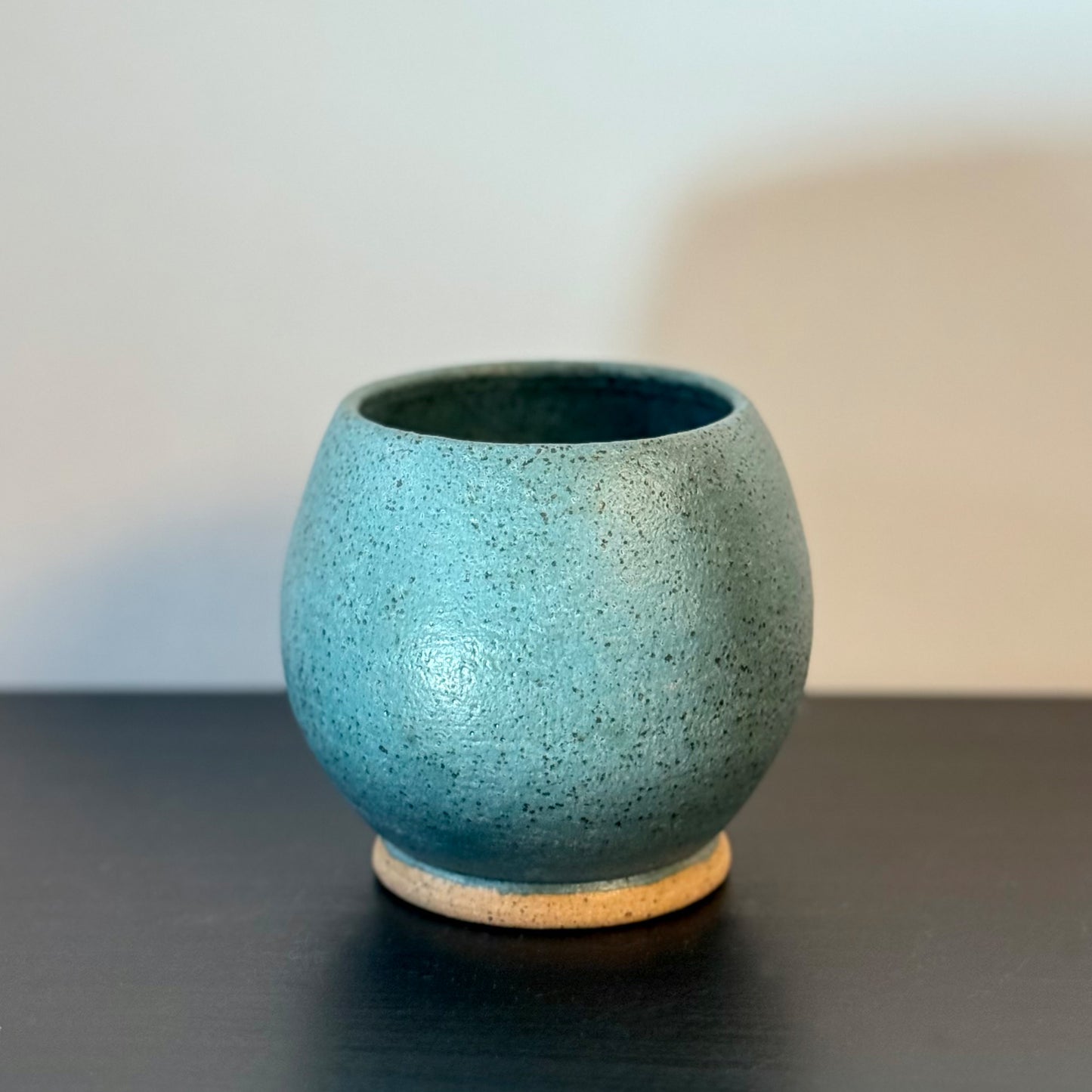 Handmade rounded ceramic vase with a saturated teal glaze, compact orb-shaped body, narrow opening, and exposed natural stoneware foot.