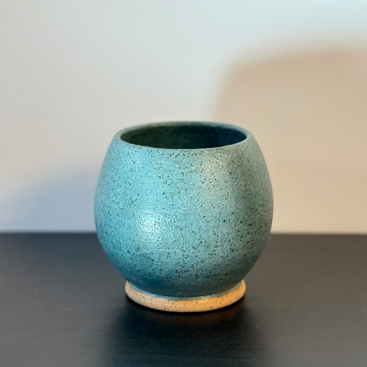 Handmade rounded ceramic vase with a saturated teal glaze, compact orb-shaped body, narrow opening, and exposed natural stoneware foot.