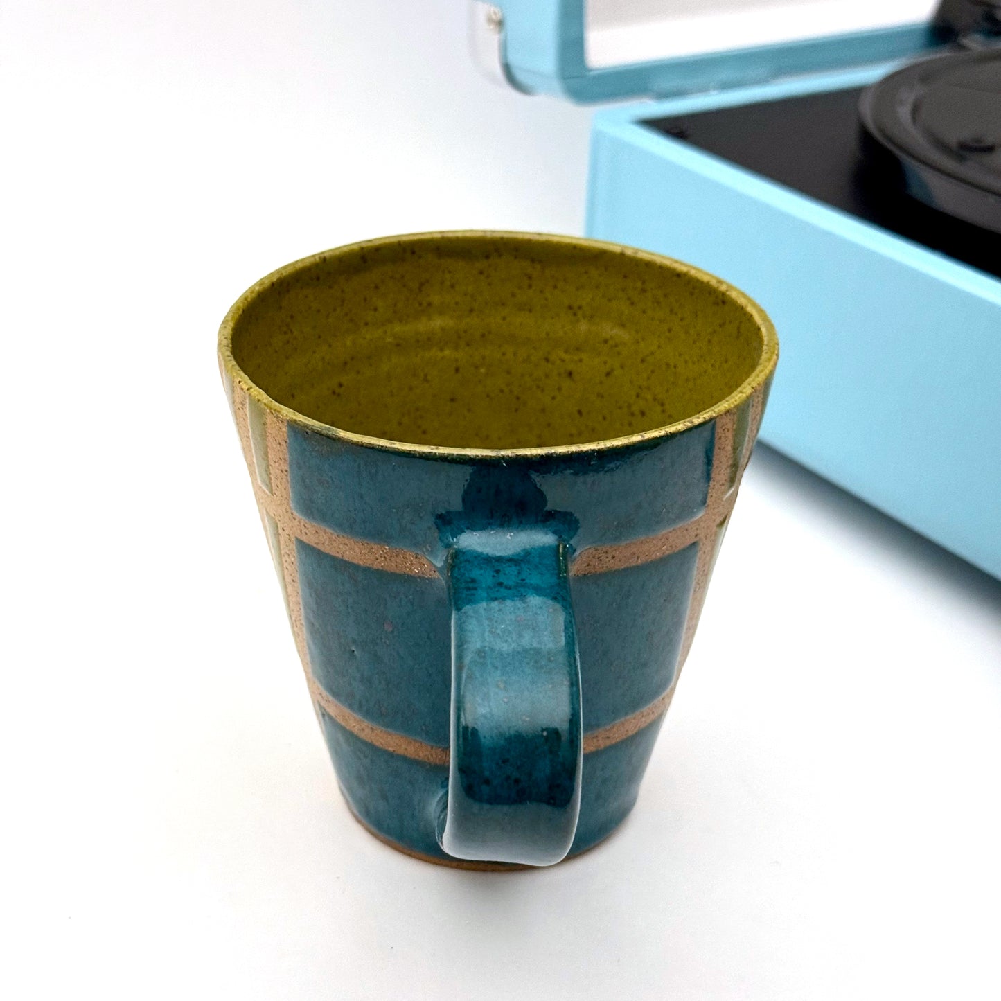 Handmade ceramic mug finished in deep teal  and olive glaze swith a mid-century–inspired intersecting pattern.