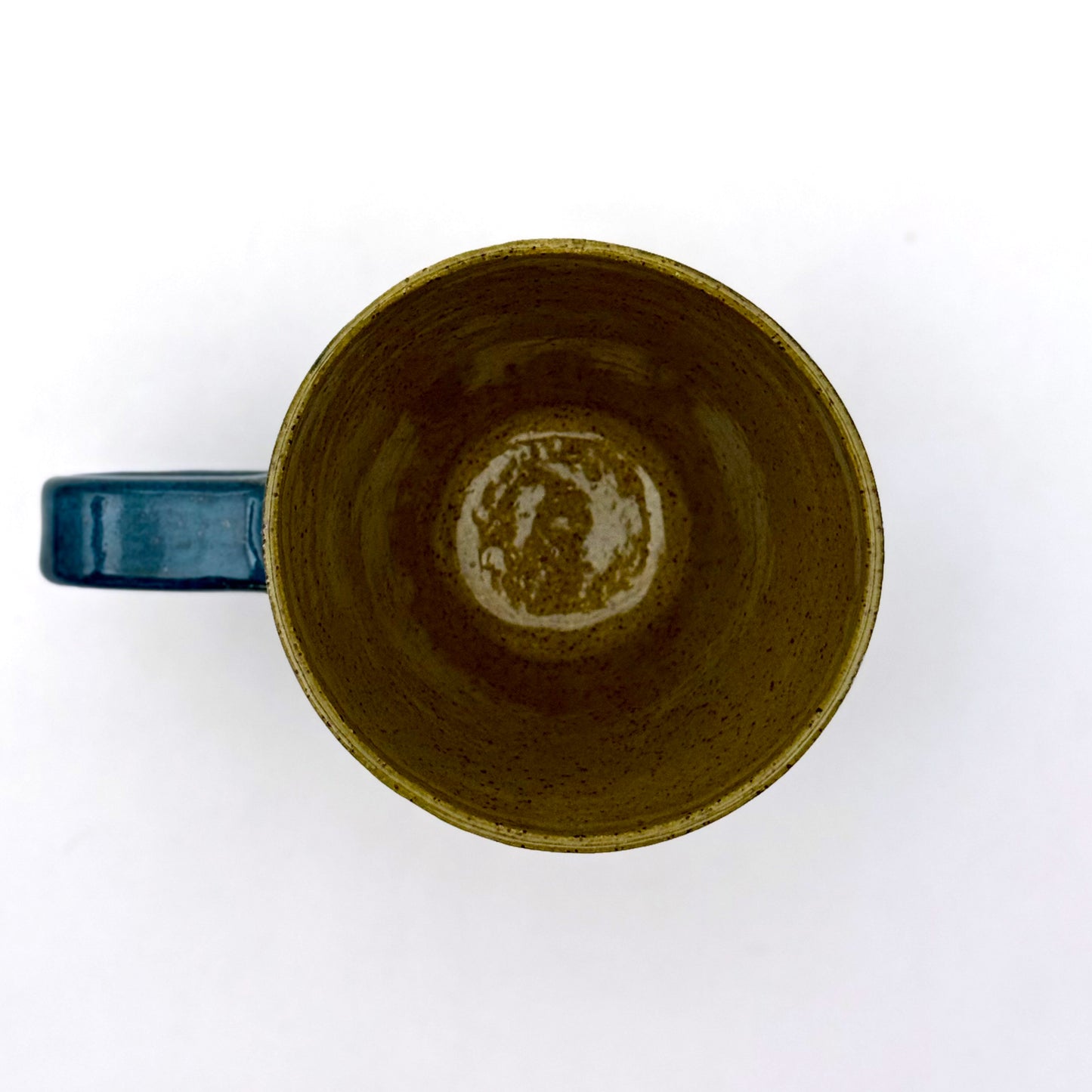 Top view of a handmade ceramic mug finished in deep teal and olive glazes with a mid-century–inspired intersecting pattern.