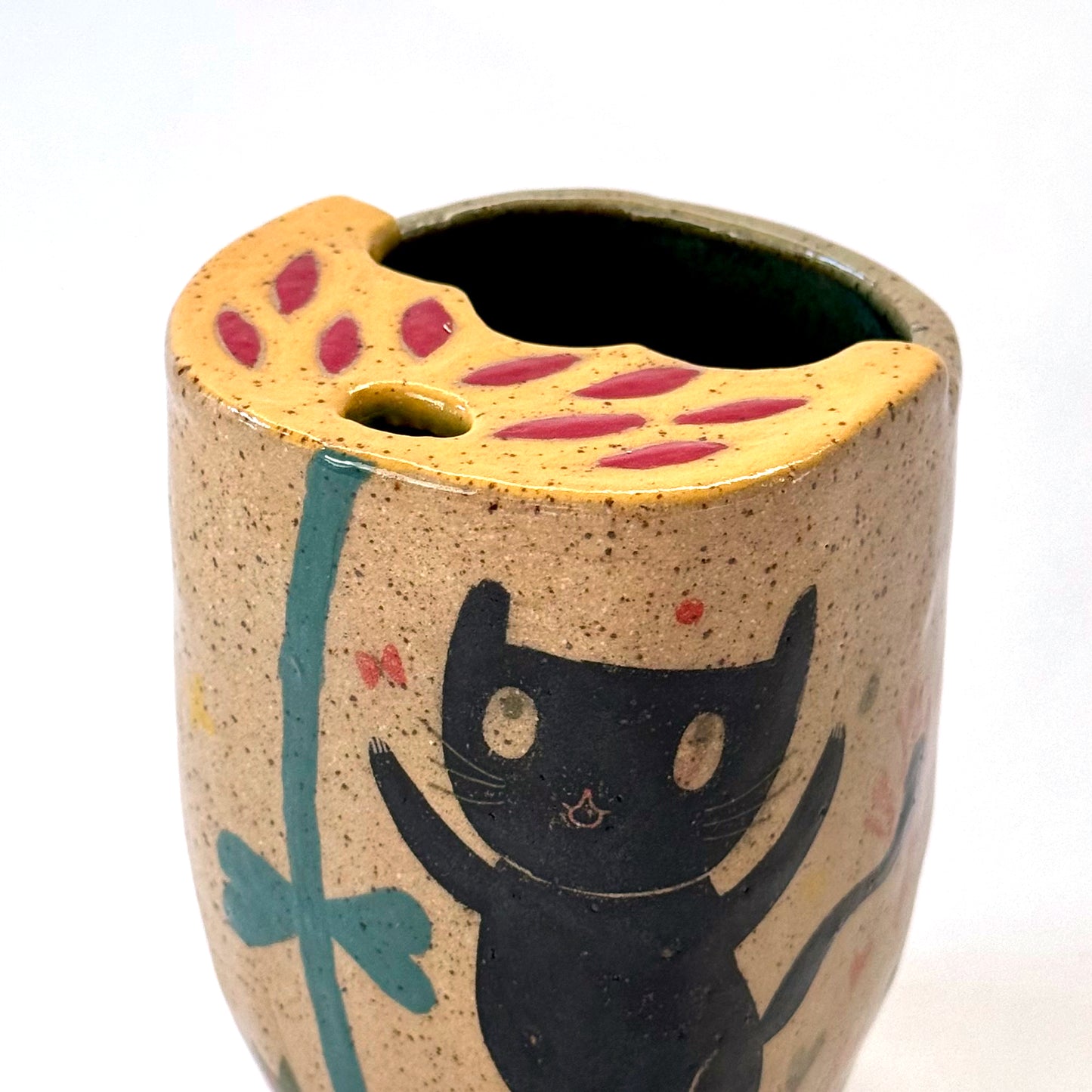 Close up of a ceramic to go mug with a black cat design on a white background